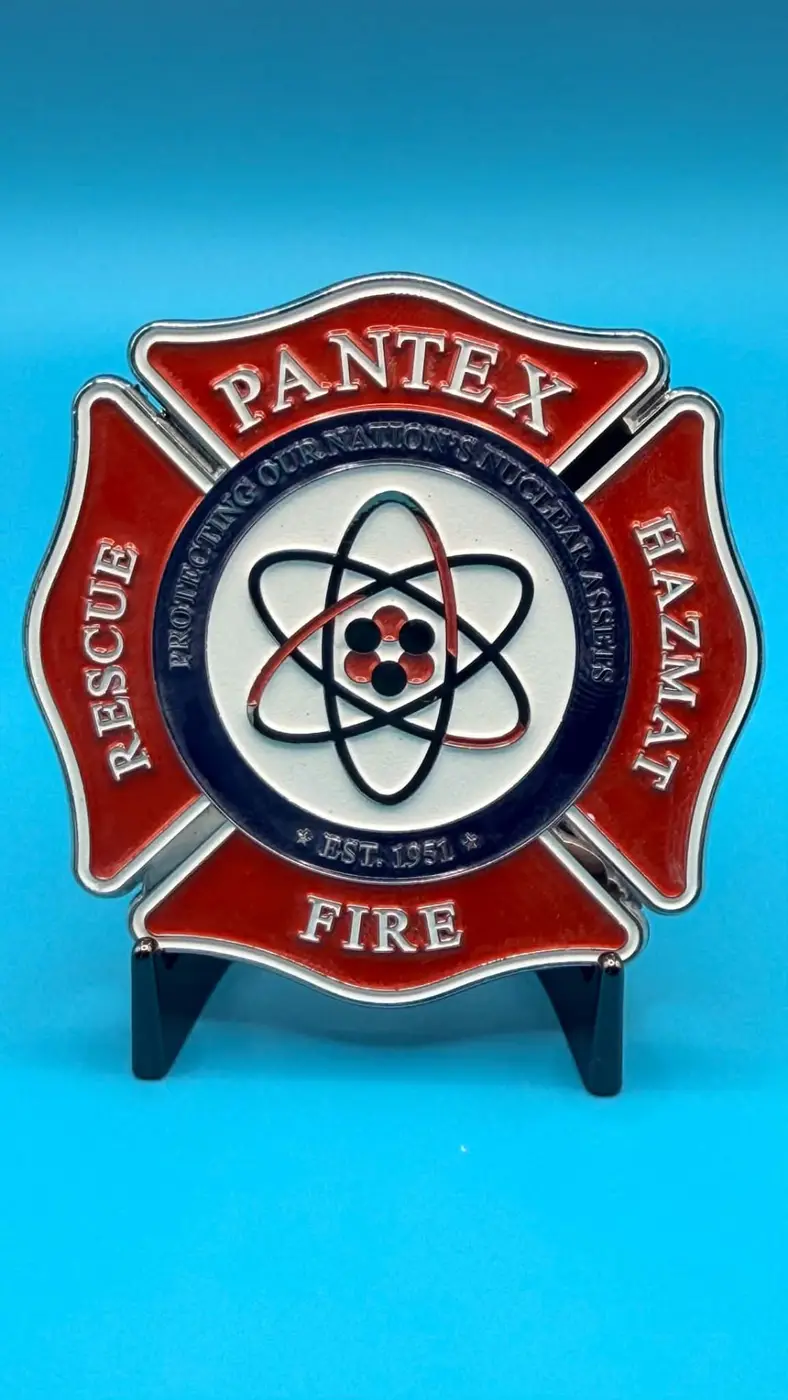 Red, white, and navy commemorative challenge coin with an atomic emblem